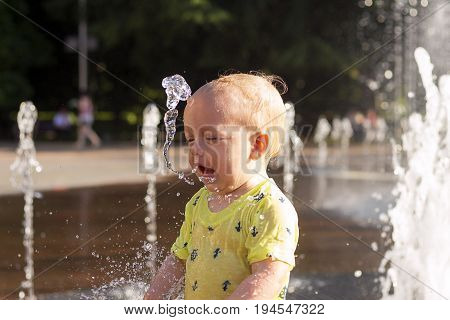 Cute Toddler With Funny Face Emotions Playiong With Frozen Stream Water In Fountain.