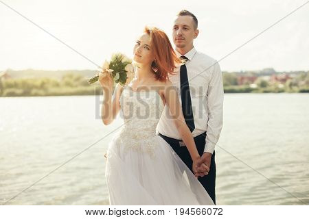 Elegant Gentle Stylish Groom And Bride Near River Or Lake. Wedding Couple In Love