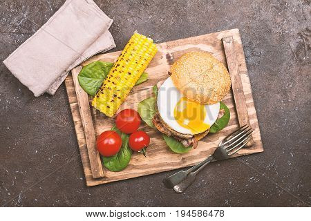 Homemmade Bacon Hamburger with fried Egg, Lettuce and lentil burger with a garnish of corn and tomatoes, top view