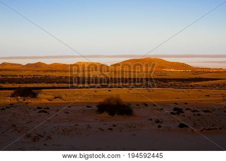 Slope hill sand on yellow dunes on blue sky background. Sunrise, morning. Sustainable ecosystem. Canary island, Fuerteventura