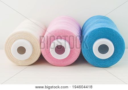sewing thread blue pink beige are on the table