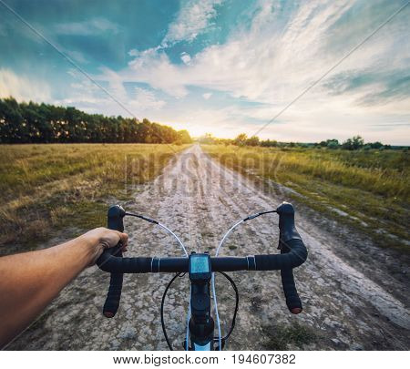 cyclist rides on the meadov dirt road on a Cyclocross bike. first-person view