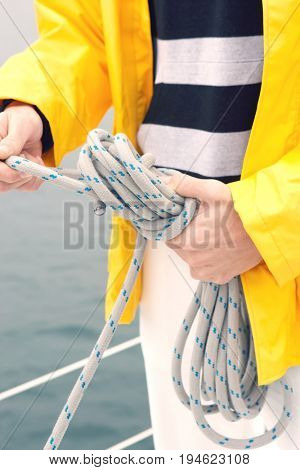 Young man tying rope on yacht, mid section