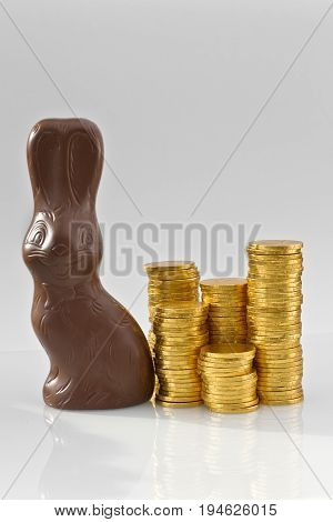 Easter bunny with golden coins, isolated on white background