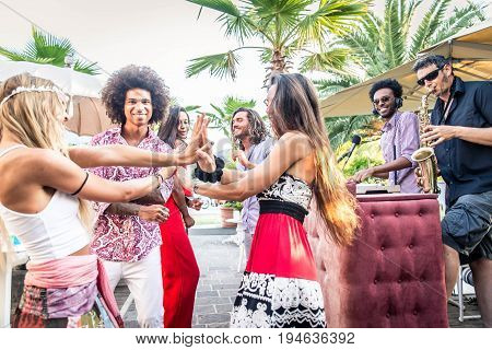 Multiethnic group of friends making party in a lounge bar - Cheerful young adults having fun and celebrating outdoors