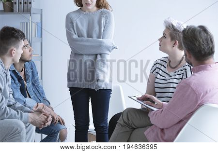Ashamed girl sharing her issues with others at group therapy
