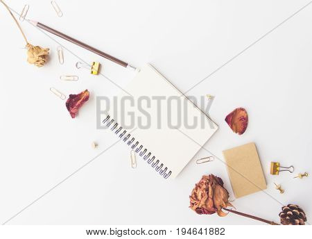 notebook paper pencil dry roses sticky note pine and paper clip on white background
