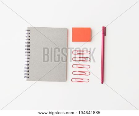 notebook paper red sticky note paper clip and pen on white background flat lay