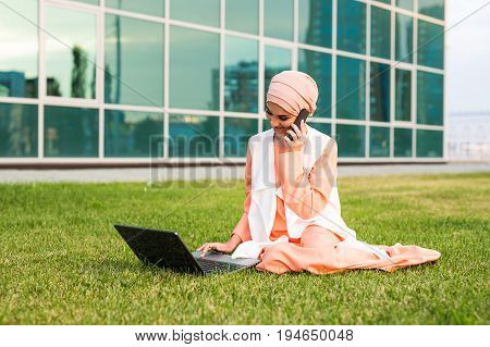 Young Muslim Woman Using Mobile Phone and Laptop In Park.