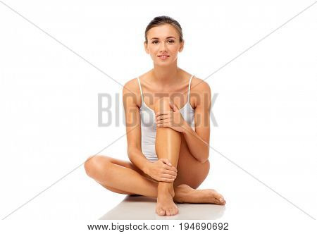 beauty, depilation, epilation, people and bodycare concept - beautiful woman touching her smooth bare legs over white background