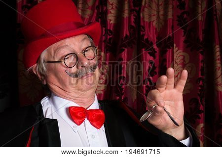 Senior illusionist on stage bending a spoon