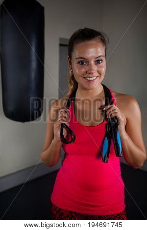 Portrait of fit woman standing with skipping rope in fitness studio