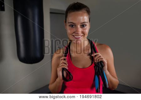 Portrait of fit woman standing with skipping rope in fitness studio