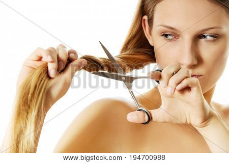 Attractive young woman is cutting her long natural hair