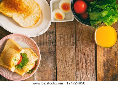 Pocket sandwich for breakfast or lunch. Sandwich with hard boiled eggs mayonnaise lettuce and tomato flat lay style for background. Top view of baked sandwich on lovely plate serve with orange juice on rustic wood table. Sandwich background.