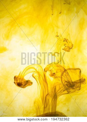 Ink swirl in a water on yellow background. The paint splash in the water. Soft dissemination a droplets of colored ink in water close-up. Abstract background. Explosion of color splashes acrylic ink.