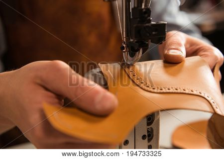 Close up of a cobbler stitching a part of the shoe at a workshop