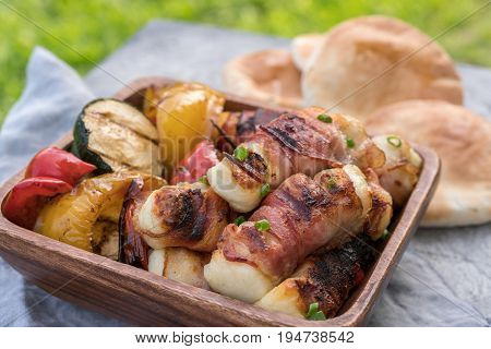 Grilled bacon wrapped haloumi cheese with vegetables and pita