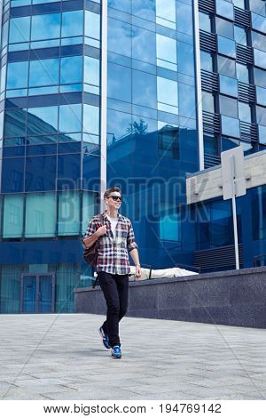 Mid shot of ositive man in sunglasses with headphones walking and listening to the music