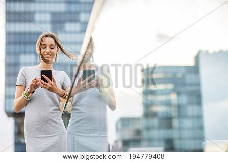 Lifestyle portrait of a business woman dressed casually standing with phone on the modern bridge in Dusseldorf city, Germany