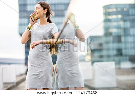 Lifestyle portrait of a business woman dressed casually standing with phone on the modern bridge in Dusseldorf city, Germany