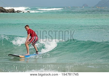 10/06/2017 Pantau Mawun Lombok Indonesia. Young man learns to surf on a long board on learner waves in a paradise location.