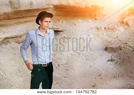 Stylish Attractive Man Stands In The Middle Of A Sand Quarry And Poses On The Camera