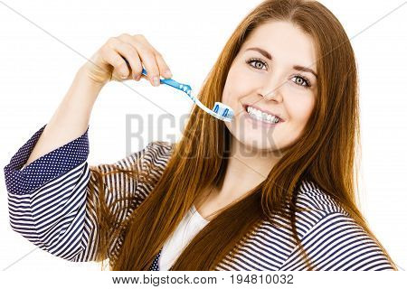 Woman wearing dressing gown holding toothbrush with paste on it. Smiling positive girl ready to cleaning teeth. Oral hygiene. Isolated on white