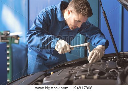Scrupulous move. Clever skilled capable man being very careful while using a wrench for drawing bolts in cars inner mechanism