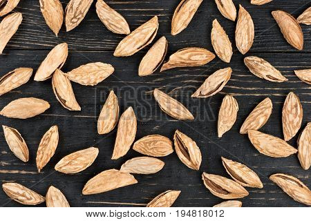 Scattered uzbek inshell almonds on wooden background