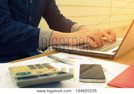 accountant or business man working with laptop computer report sheet calculator smartphone notebook and pen finances and calculate on desk savings business economy concept sunlight effect