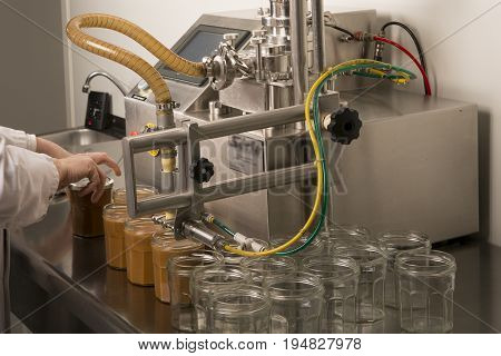 Automated food factory machine get the caramel jam in the jugs. Close up