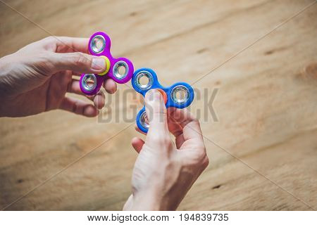 A Man Hand Holding Hand Spinner Or Fidget Spinner Over Wooden Background