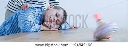 Autistic boy observing a colorful spinning top with his therapist