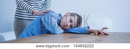 Autistic boy lying on desk being comforted by his therapist