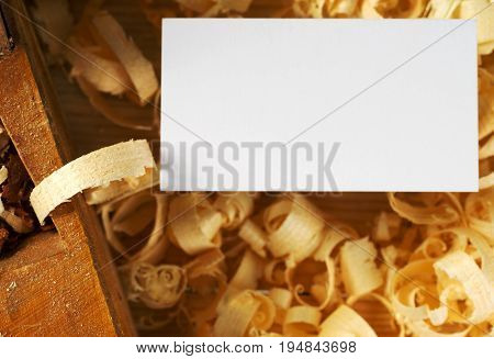 Blank business card on wooden table for carpenter tools with sawdust top view.