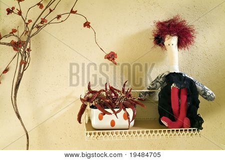 bambola di pezza rossa seduto su una mensola accanto a ciotola con peperoncino