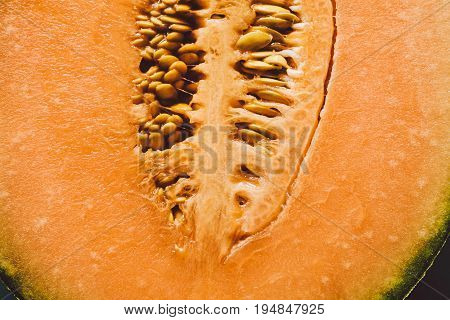 Melon seeds background and texture. Close up view of melon cut in a half with seeds. Organic texture and background. Fresh fruit. Macro view of melon surface. Melon texture. Healthy food.