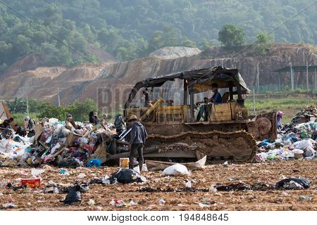 Kota Kinabalu, Malaysia - 09 July, 2017: Scavenger And An Aged Bulldozer  Pushing A Garbage At Landf