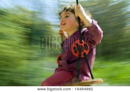 lachende jongen op een schommel met motion blur