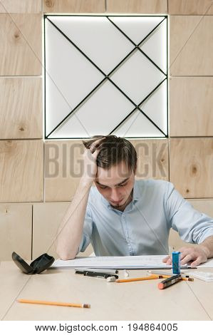 Designer's problem and stress, brainstorm, new invention concept. Brainwork in office. Young man intencively thinking on work in his workplace