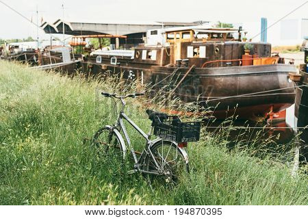Vintage bike parked near liveaboard boat on a river - summer travel discovery of unusual places