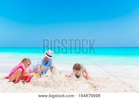 Family making sand castle at tropical white beach
