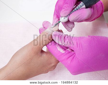 Hardware manicure closeup . Removal of old gel varnish in the salon. Manicure master doing beauty procedure for client top view