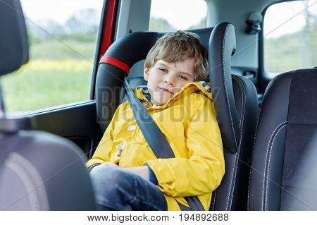Tired preschool kid boy sitting in car during traffic jam. Sad little school child in safety car seat with belt enjoying trip and jorney. Safe travel with kids and traffic laws concept.