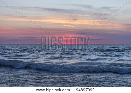 Waves Crashing And Rolling In Near Sea Shore Under A Pastel Sky After Sunset