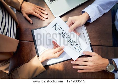 Hand Of A Businessman Hands Over A Resignation Letter On A Wooden Table To His Boss