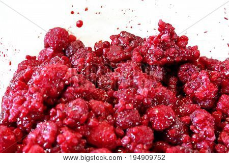 Healthy red rasperries on a white background with splash of raspberry juice