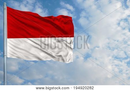 National flag of Monaco on a flagpole in front of blue sky.
