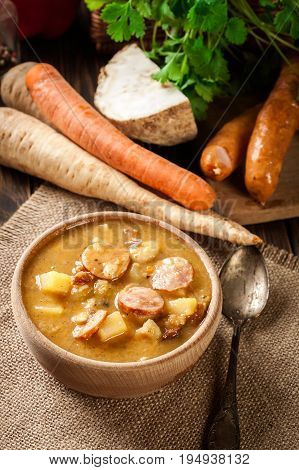 Wooden Bowl Of Split Pea Soup With Sausage And Potatoes